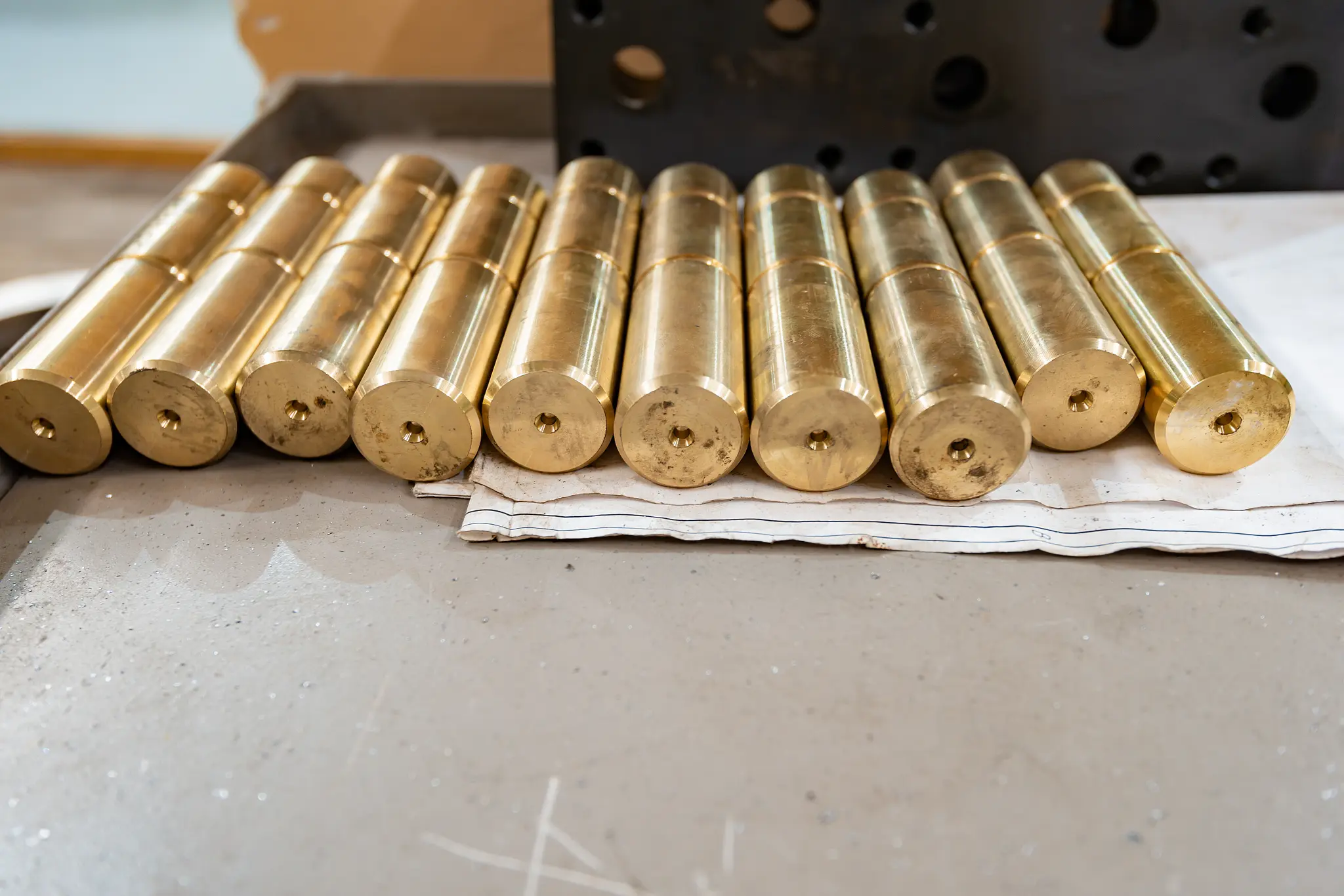 A production row of freshly machined brass components on the shop floor